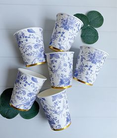 six blue and white cups sitting next to each other on top of a green plant