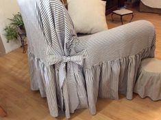 a chair with a striped cover on it sitting in a living room next to a footstool