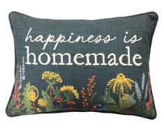 a pillow that says happiness is homemade with flowers and plants on the front in white lettering