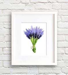 a white frame hanging on a brick wall with a painting of purple flowers in it