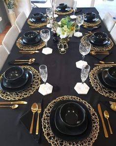 black and gold table setting with place settings for four people to sit at the dinner table