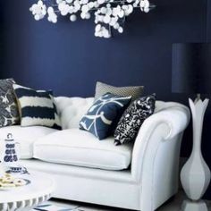 a living room with white couches and blue accent wall paint on the walls, along with black and white accessories