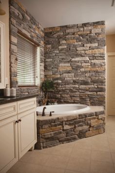 a bathroom with a stone wall and tub next to a window in the shower area