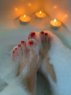 a woman's feet in a bathtub with candles