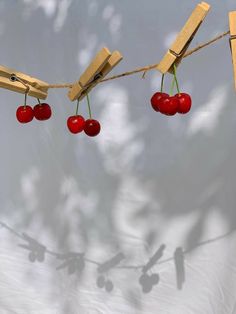 three cherries are hanging on a clothes line with clothes pegs attached to them