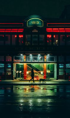 a person walking down the street in front of a store at night with red lights