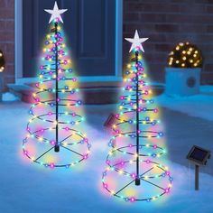 two lighted christmas trees in the snow