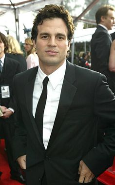 a man in a suit and tie standing on a red carpet at an awards event