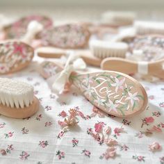 some pink and white hairbrushes on a floral table cloth with other items in the background