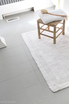 a bathroom with a white rug on the floor and a wooden stool in the middle