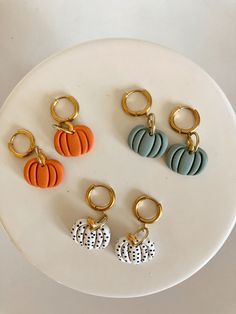 four pumpkin key chains on a white plate