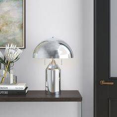 a table with two books and a lamp on it next to a door in a room