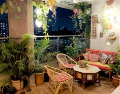 a living room filled with lots of plants next to a balcony at night or in the evening