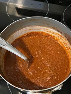 a pot on the stove with some food in it and a spoon sticking out of it