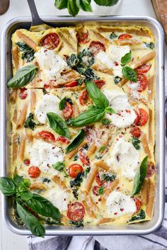 a square casserole dish with spinach, tomatoes and mozzarella cheese