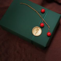 a green gift box with a gold medal and red berries on the ribbon around it