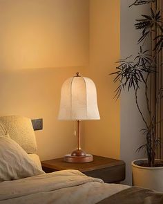 a bedroom with a bed, lamp and plant in the corner on the side table