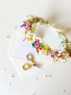 a flower crown is sitting on top of a white table with scissors and pearls scattered around it