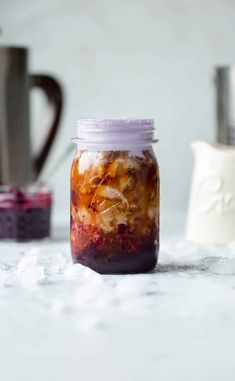 a jar filled with food sitting on top of a table next to two cups and spoons