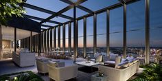 a living room filled with white furniture and large windows overlooking the cityscape at night