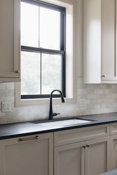 an empty kitchen with white cabinets and black counter tops is seen in this image from the window