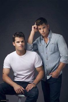 two young men sitting on stools posing for the camera with one holding his hand to his head