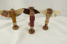 three small wooden angel figurines sitting on top of a white cloth covered surface