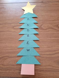 a christmas tree made out of paper on top of a wooden table with the word and arrow cut out