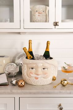 a kitchen counter topped with bottles of champagne and an old fashioned santa claus face bowl