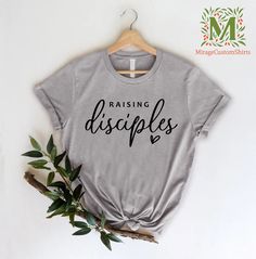 "Raising Disciples Shirt,Christian Mom Tshirts,Bible Verse Tee for Mom,Faith Shirts,Religious Women Tee,Shirt for Women, Gift for Mother --- How To Order ----- 1-) Please, check and review all the photos. 2-) Choose your t-shirt size and color. *Different styles of shirts may have different shades of same color choice due to different manufacturer brands. *For this reason, we recommend you to match shirts from the same styles if you want precisely matching colors (ex. Unisex, V-necks, Toddler, e Mother’s Day With Cricut, Raising Disciples, Religious Tshirts, Faith Shirts, Faith Tshirts, Bible Verse Tees, Cricut Inspiration, Motherhood Shirts, Christian Shirts Designs