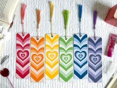 four colorful bookmarks with hearts on them next to an open book and other items