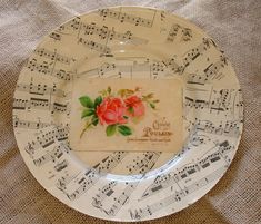 a plate with sheet music on it and roses painted on the side, sitting on a tablecloth