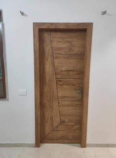 an open wooden door in a room with white walls and tile flooring on the ground