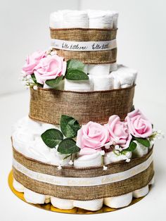 a three tiered diaper cake decorated with pink roses and burlap ribbon