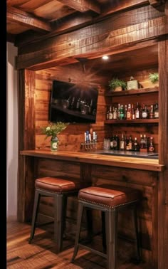 a wooden bar with two stools and a television mounted on the wall above it