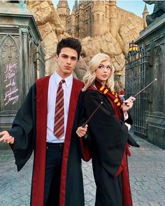 two people dressed in harry potter costumes posing for a photo outside hogwart's castle