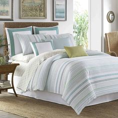 a bed with blue and green striped comforters in a room next to a table