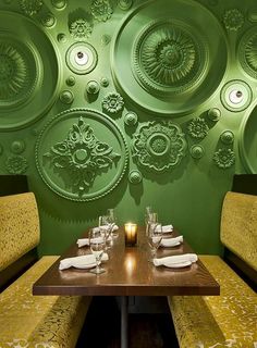 a table with place settings in front of a green wall and circular medallions on the wall