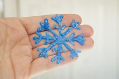 a hand holding a small blue snowflake in it's palm