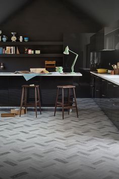 two stools are in the middle of a kitchen with black walls and flooring