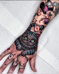 a person's hand with tattoos on it and a cat holding a clock in the middle