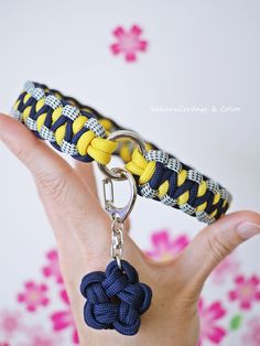 a hand holding a yellow and blue rope keychain with a knot on it