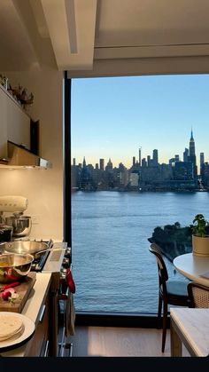 a kitchen with a view of the water and buildings in the distance is seen from across the room