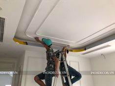 a man on a ladder painting the ceiling