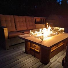 a fire pit sitting on top of a wooden deck next to a couch and table