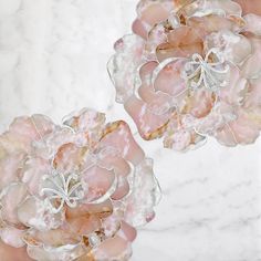 two pink flowers are shown in front of a marble background with white and gold accents