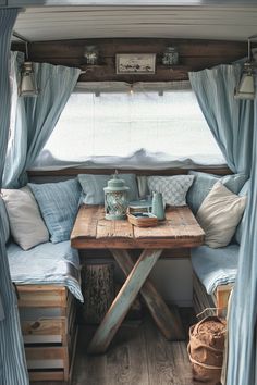 the inside of a camper with blue curtains and pillows on it's side