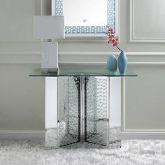 a glass table with two vases and a mirror in the middle on a white rug