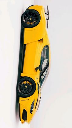 a yellow sports car hanging from the side of a white wall with black rims