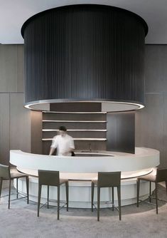 a man standing in front of a counter with chairs around it and a round table